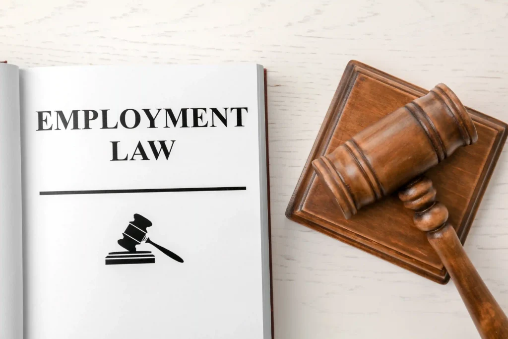 A wooden gavel rests beside an open book labeled "Employment Law" .